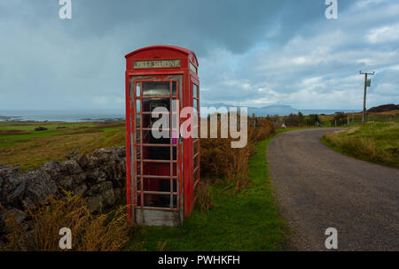 Vecchio telefono rosso scatola, abbandonati e defunta in un villaggio rurale nelle Highlands della Scozia si affaccia l'isola delle Ebridi di Eigg. Foto Stock