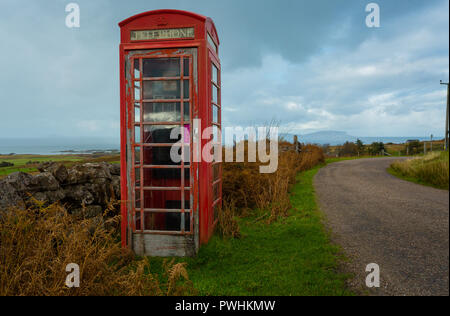 Vecchio telefono rosso scatola, abbandonati e defunta in un villaggio rurale nelle Highlands della Scozia si affaccia l'isola delle Ebridi di Eigg. Foto Stock