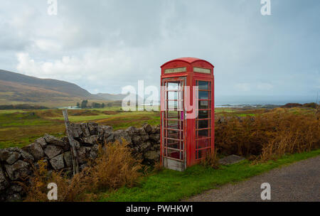 Vecchio telefono rosso scatola, abbandonati e defunta in un villaggio rurale nelle Highlands della Scozia si affaccia l'isola delle Ebridi di Eigg. Foto Stock