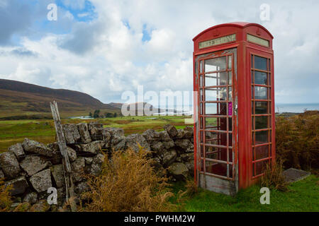 Vecchio telefono rosso scatola, abbandonati e defunta in un villaggio rurale nelle Highlands della Scozia si affaccia l'isola delle Ebridi di Eigg. Foto Stock