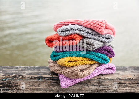 Righe colorate cappelli a maglia per la vendita su sfondo naturale. Una colorata collezione di bobble hats allineati Foto Stock