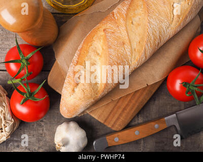 Organico gustoso pane baguette con ingredienti mediterranei su un rustico tavolo da cucina Foto Stock