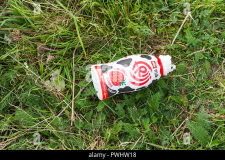 Scartato Muller sapore di fragola frullato bottiglia tra erba e piante infestanti, Dorset, Regno Unito Foto Stock