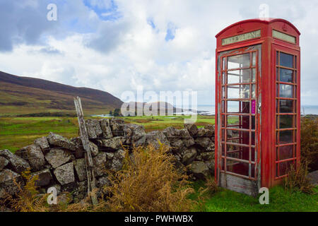 Vecchio telefono rosso scatola, abbandonati e defunta in un villaggio rurale nelle Highlands della Scozia si affaccia l'isola delle Ebridi di Eigg. Foto Stock