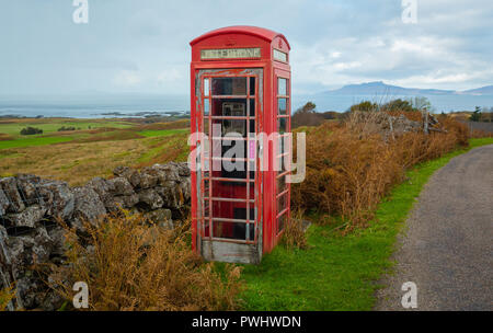 Vecchio telefono rosso scatola, abbandonati e defunta in un villaggio rurale nelle Highlands della Scozia si affaccia l'isola delle Ebridi di Eigg. Foto Stock