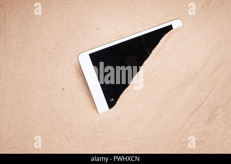 Tablet mobile display schermo coperto di sabbia in spiaggia danneggiato e la perdita di indennizzo assicurativo Foto Stock