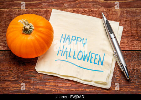 Happy Halloween saluti - scrittura su un tovagliolo con una zucca zucca contro il fienile rustico legno Foto Stock