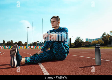 L'accoppiamento maschio runner stretching gambe la preparazione per eseguire durante la formazione a stadium tracce. L'atleta, fitness, ginnastica, sport, esercizio, formazione atletico e concetto di stile di vita Foto Stock