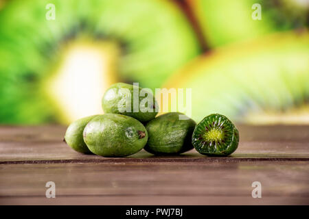 Il gruppo di cinque tutta una metà del fresco verde mini baby kiwi con fette di kiwi in background Foto Stock