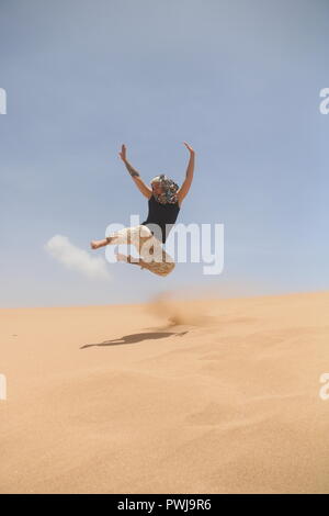 La donna nel deserto il salto di una duna Foto Stock