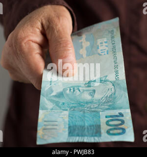 Denaro dal Brasile, valuta brasiliana. Vista frontale della vecchia donna di mano le bollette di manipolazione. Foto Stock