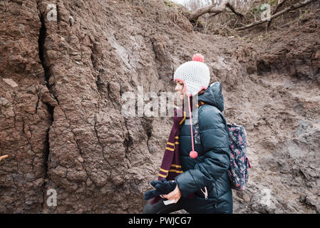 Piccola ragazza in ricerca di fossili, sul francese della zona costiera, la massa di argilla, parte della collina con resti di fossili. Foto Stock