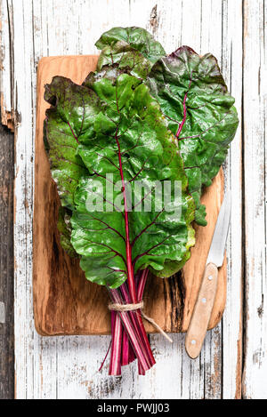 Bieta foglie su sfondo di legno. Vista dall'alto. Verde, vegano vegetariano o pulire il concetto di mangiare Foto Stock