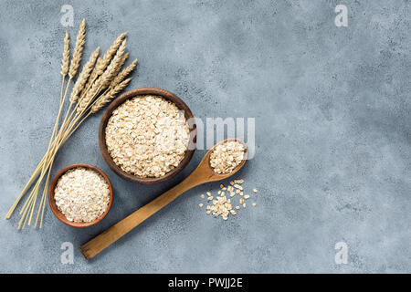 Avena, fiocchi d'avena e fiocchi di avena in ciotola di legno, vista dall'alto. Concetto di mangiare sano, uno stile di vita sano, dieta e cibo vegetariano Foto Stock