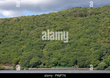 Motore a vapore e carrozze da Llanberis Lake Railway la cottura a vapore lungo accanto al lago Llynpadarn, Llanberfis Foto Stock