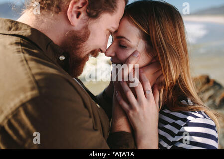 Close up di barba uomo con la donna di toccare la loro fronte a una spiaggia. Coppia romantica sulla spiaggia. Foto Stock