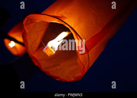 Vista ravvicinata di due cinesi lanterne volanti con fuoco ardente all'interno oltre il profondo blu del cielo notturno Foto Stock