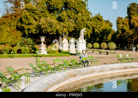 Parigi, Francia - 01 Settembre 2018: Donna seduta sulla famosa sedie verdi in Tuileries parco vicino alla fontana a Parigi Foto Stock