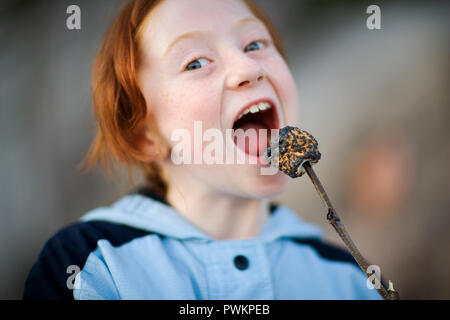 Ritratto di una ragazza di mangiare un olocausto marshmallow. Foto Stock