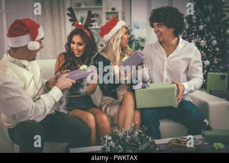 Due giovani allegro giovane festeggia il nuovo anno a casa. Si stanno divertendo e dando molti dono all'altro. Foto Stock