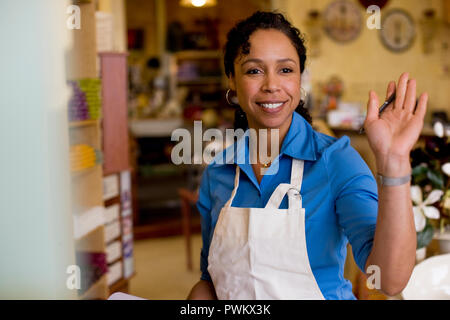 Addetto alle vendite in piedi in store sventolando Foto Stock