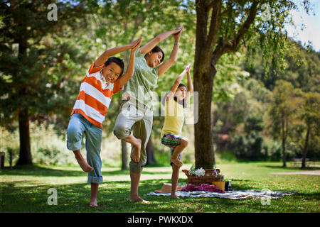 Madre la pratica dello yoga pone con i suoi due figli. Foto Stock