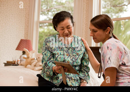 Donna senior di ricevere una visita a casa dal suo infermiere. Foto Stock