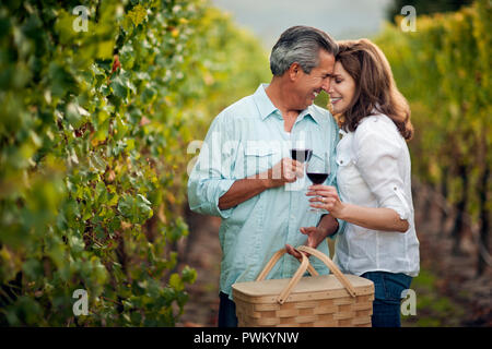 Coppia matura la condivisione di un intimo momento mentre si beve il vino rosso in vigna. Foto Stock