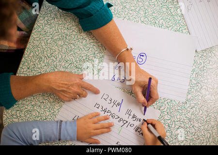 Donna matura aiutare un giovane ragazzo con la matematica. Foto Stock