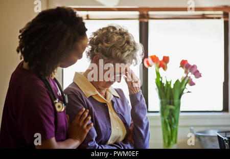 Giovane infermiere consolante un lutto donna senior. Foto Stock