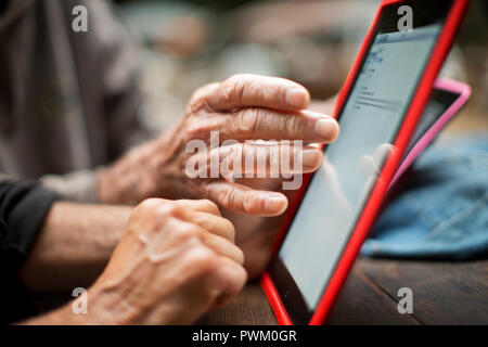 Le mani di un anziano uomo e donna matura utilizzando una tavoletta digitale. Foto Stock