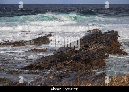 Enorme aqua onde con schiuma bianca la laminazione in una spiaggia rocciosa in corrispondenza del punto di Buckquoy vicino Birsay, isole Orcadi Scozia in una giornata di sole, con battenti spray Foto Stock