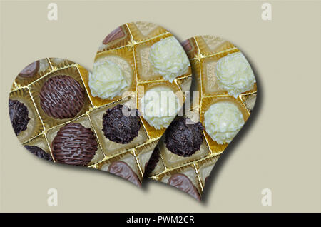 Due cuori con cioccolatini e biscotti su sfondo beige, close up, full frame, orizzontale inclinato. Foto Stock