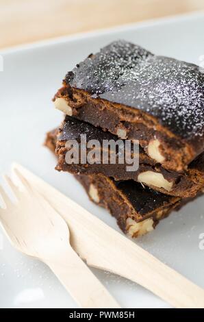 Tre brownies con dadi accanto alle posate in legno Foto Stock