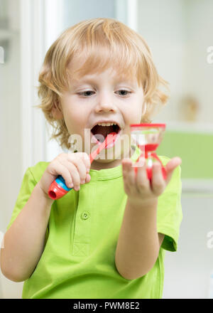 Bambino ragazzo la pulizia i suoi denti e guardando la clessidra Foto Stock