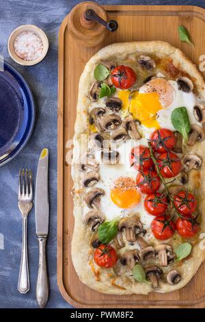 La prima colazione la pizza con le uova, i funghi e i pomodori ciliegia Foto Stock