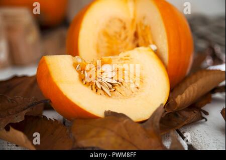 Una zucca tagliata a fette su foglie autunnali Foto Stock