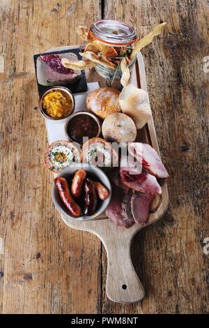 Un plowman pranzo piatto di prosciutto, salsicce, uova di Scotch, chutney, decapare e panini (Inghilterra) Foto Stock