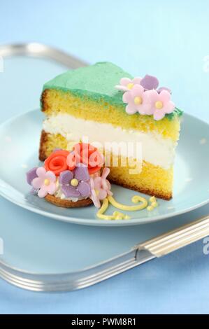 Un pezzo di torta genovese con fondente fiori Foto Stock