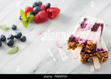 Yogurt, berry e granola popsicles colazione sulla superficie di marmo Foto Stock