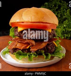 Doppio Cheeseburger con bacon, pomodori e lattuga Foto Stock