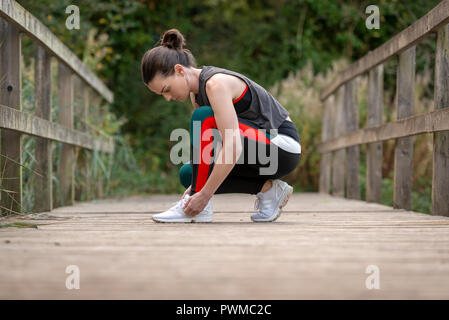 Donna sportiva di vincolare il suo formatori prima di esercizio e in esecuzione Foto Stock