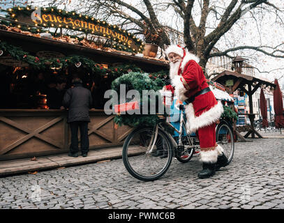 Monaco di Baviera, Germania - 6 Dicembre 2017: Santa Claus aziona una bicicletta decorata con regali sul mercato di Natale Rindermarkt a Monaco di Baviera. Foto Stock
