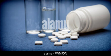 Alcune fiale medicina con pastilllas bianco isolato su sfondo blu Foto Stock