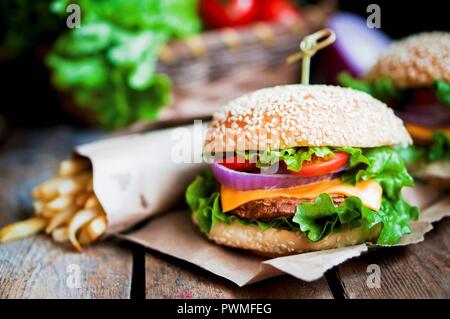 Cheeseburger con cipolle, pomodori, lattuga e trucioli Foto Stock