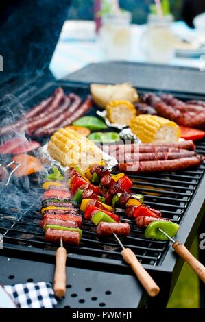 Spiedini di salsiccia, salsicce e verdure su un barbecue Foto Stock