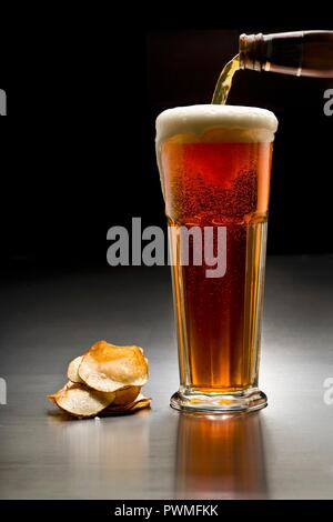 Un bicchiere di birra scura e patatine Foto Stock