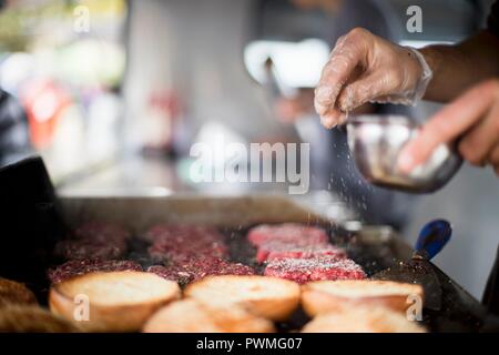 Patties di carne essendo condito con sale Foto Stock