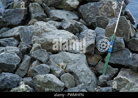 Fly Canna da pesca e Mulinello di pietra sulla riva del fiume. Scena di pesca sulle sponde. Foto Stock