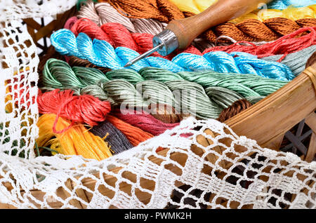 Cestello Vintage con un kit da cucito, multi-fili colorati su sfondo di tessuto,a mano in pizzo di maglia Foto Stock